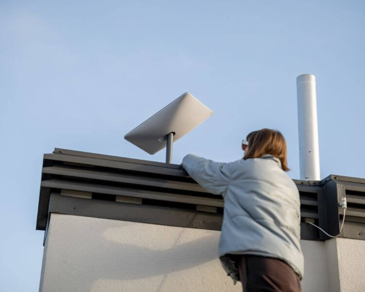 Mujer instalando la antena de internet por satélite de Zafiro Telecom en su tejado